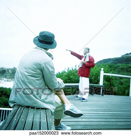Mature woman sitting on bench, man pointing toward sea. View Large Photo Image Stock Image - Mature woman sitting on bench, man pointing toward sea.. Fotosearch