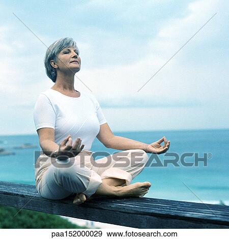 Mature woman sitting on wooden rail in lotus position, portrait. View Large Photo Image Stock Photo - Mature woman sitting on wooden rail in lotus position, portrait.. Fotosearch