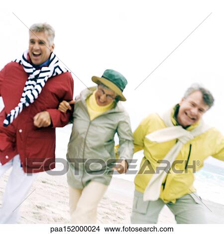 Three mature friends arm in arm on beach, portrait. View Large Photo Image Picture - Three mature friends arm in arm on beach, portrait.. Fotosearch