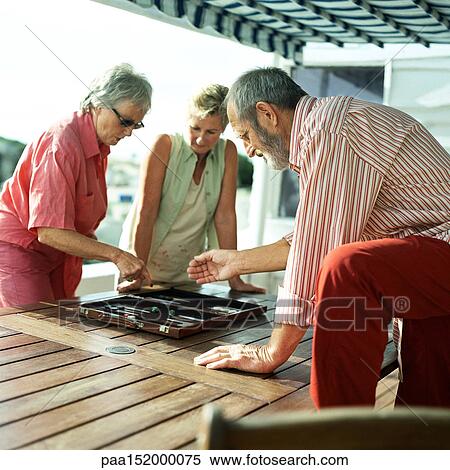Three mature friends playing backgammon. View Large Photo Image Stock Photography - Three mature friends playing backgammon.. Fotosearch