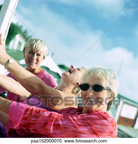 Stock Image - Three mature women laughing, two looking into camera.. Fotosearch