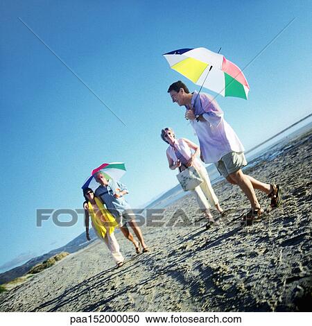 Two mature couples standing on beach, men holding umbrellas. View Large Photo Image Stock Image - Two mature couples standing on beach, men holding umbrellas.. Fotosearch