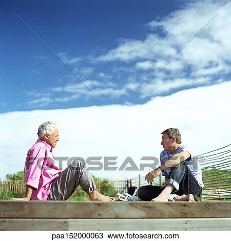 Stock Image - Two mature men sitting face to face.. Fotosearch