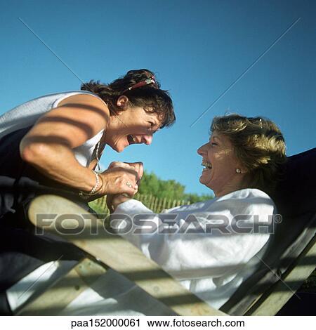 Stock Image - Two mature women face to face, laughing, portrait.. Fotosearch