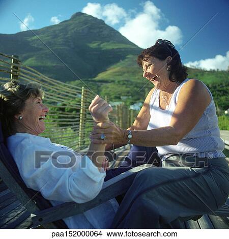 Two mature women playfighting, mountains in background. View Large Photo Image Picture - Two mature women playfighting, mountains in background.. Fotosearch