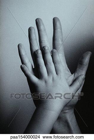 Picture - Child's hand against man's hand, palm to palm, close-up, b&w.. Fotosearch