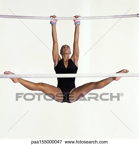 Female gymnast performing on uneven bars.. View Large Photo Image Stock Photo - Female gymnast performing on uneven bars... Fotosearch