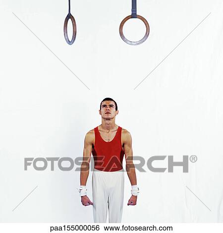 Male gymnast standing under rings, looking up. View Large Photo Image Stock Photograph - Male gymnast standing under rings, looking up.. Fotosearch