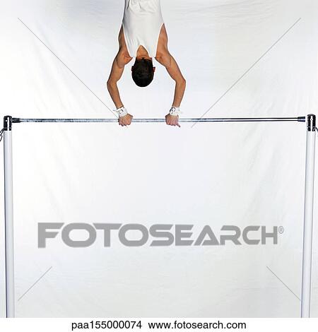 Male gymnast swinging on horizontal bar, upper section, rear view. View Large Photo Image Picture - Male gymnast swinging on horizontal bar, upper section, rear view.. Fotosearch