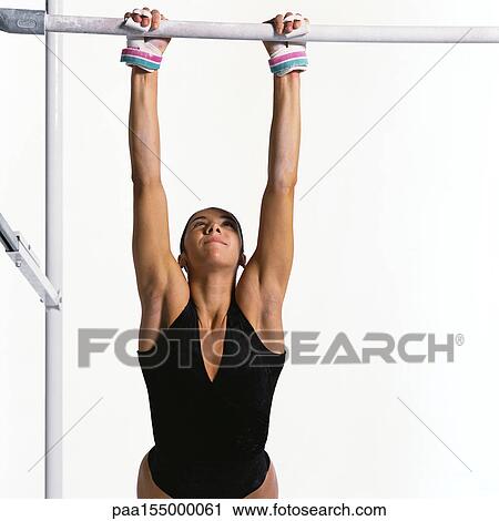 Stock Image - Young female gymnast grasping horizontal bar.. Fotosearch
