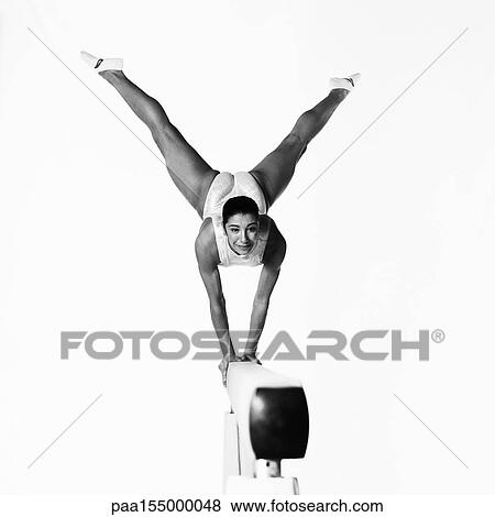 Young female gymnast on balance beam, looking into camera, b&w. View Large Photo Image Stock Photo - Young female gymnast on balance beam, looking into camera, b&w.. Fotosearch