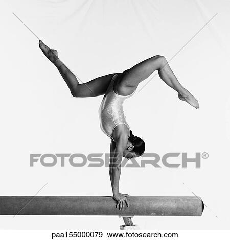 Young female gymnast on balance beam performing routine, side view, b&w. View Large Photo Image Stock Photo - Young female gymnast on balance beam performing routine, side view, b&w.. Fotosearch