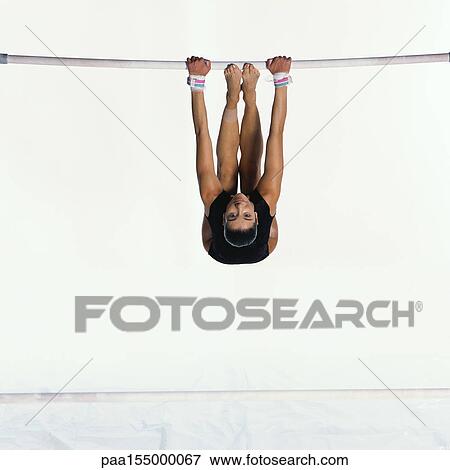 Young female gymnast performing on uneven bars, looking into camera. View Large Photo Image Stock Photo - Young female gymnast performing on uneven bars, looking into camera.. Fotosearch