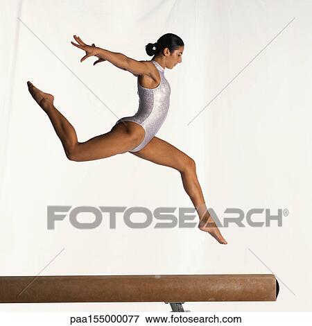 Young female gymnast performing on balance beam, mid-flight, side view. View Large Photo Image Stock Photo - Young female gymnast performing on balance beam, mid-flight, side view.. Fotosearch