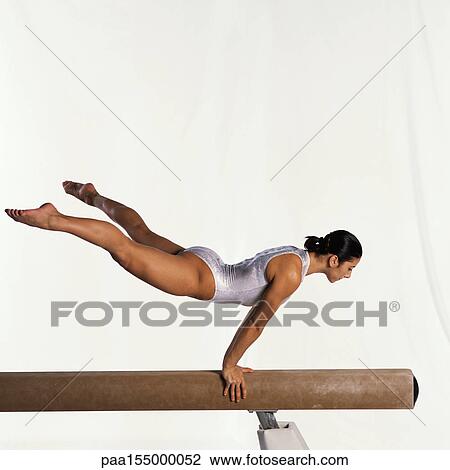 Young female gymnast performing routine on balance beam, side view. View Large Photo Image Stock Image - Young female gymnast performing routine on balance beam, side view.. Fotosearch