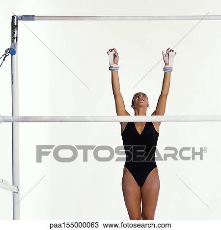 Young female gymnast reaching up toward uneven bars. View Large Photo Image Stock Image - Young female gymnast reaching up toward uneven bars.. Fotosearch