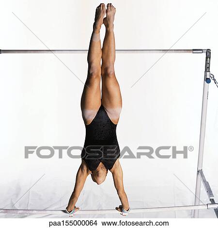 Young female gymnast swinging on uneven bars. View Large Photo Image Picture - Young female gymnast swinging on uneven bars.. Fotosearch