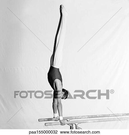 Young male gymnast doing handstand on parallel bars, side view. View Large Photo Image Stock Image - Young male gymnast doing handstand on parallel bars, side view.. Fotosearch