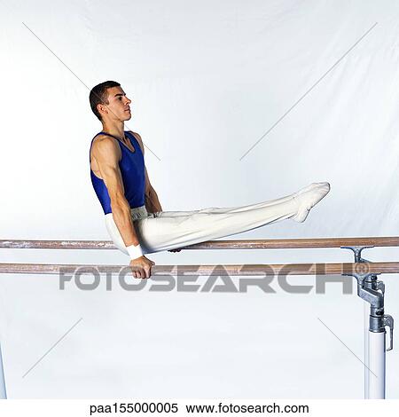 Stock Photography - Young male gymnast on parallel bars, side view.. Fotosearch