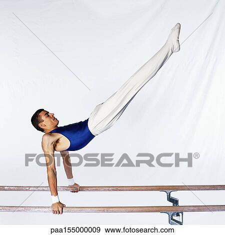 Young male gymnast performing routine on parallel bars, side view. View Large Photo Image Stock Photo - Young male gymnast performing routine on parallel bars, side view.. Fotosearch