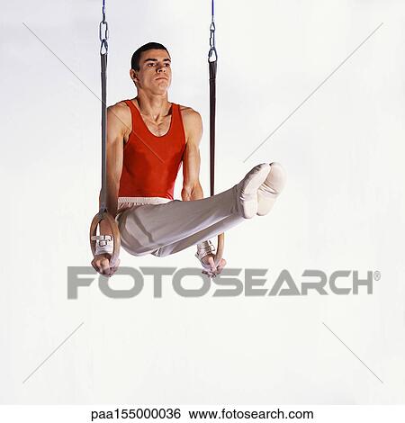 Stock Photograph - Young male gymnast performing routine on rings.. Fotosearch