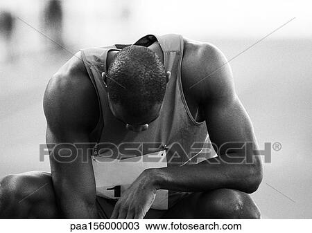 Stock Image - Male athlete crouching, head down, close-up, b&w. Fotosearch