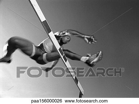 Male athlete jumping hurdle, low angle view, blurred motion, b&w View Large Photo Image Stock Photograph - Male athlete jumping hurdle, low angle view, blurred motion, b&w. Fotosearch
