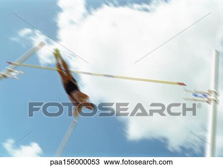Stock Image - Male pole vaulter in mid-air, blurred motion. Fotosearch