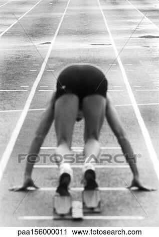 Stock Image - Male runner at starting block, rear view, b&w. Fotosearch