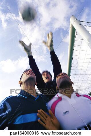 Goal keeper reaching for the ball behind two other players during a match. View Large Photo Image Stock Photograph - Goal keeper reaching for the ball behind two other players during a match.. Fotosearch
