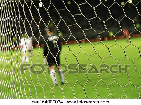 Goal keeper standing in front of goal during a match, blurred, seen from behind net. View Large Photo Image Picture - Goal keeper standing in front of goal during a match, blurred, seen from behind net.. Fotosearch