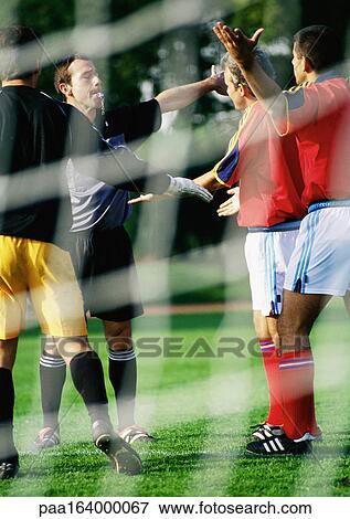 Referee and soccer players during a match, seen from behind the goal net. View Large Photo Image Stock Photo - Referee and soccer players during a match, seen from behind the goal net.. Fotosearch