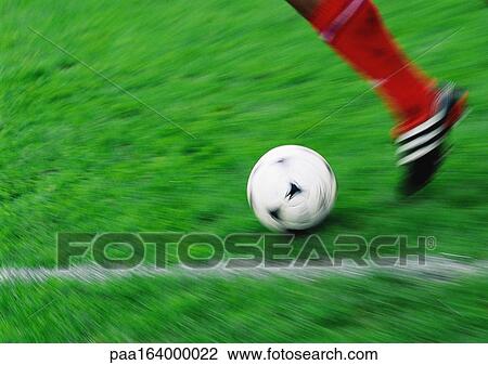 Stock Image - Soccer player running with ball, blurred, low section.. Fotosearch