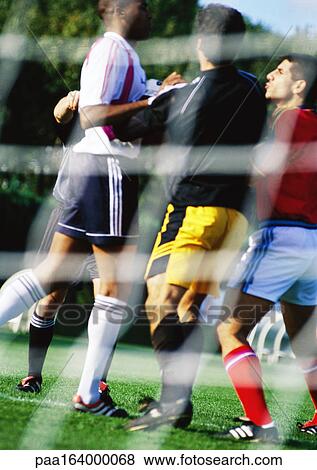 Soccer players during a match, seen from behind the goal net. View Large Photo Image Stock Photo - Soccer players during a match, seen from behind the goal net.. Fotosearch