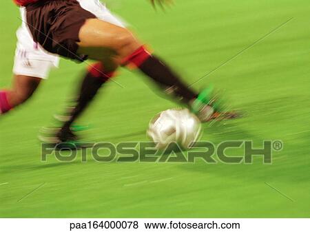 Stock Photo - Soccer players running with ball, lower section, blurred.. Fotosearch