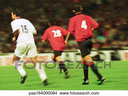 Three soccer players running, rear view, blurred. View Large Photo Image Picture - Three soccer players running, rear view, blurred.. Fotosearch