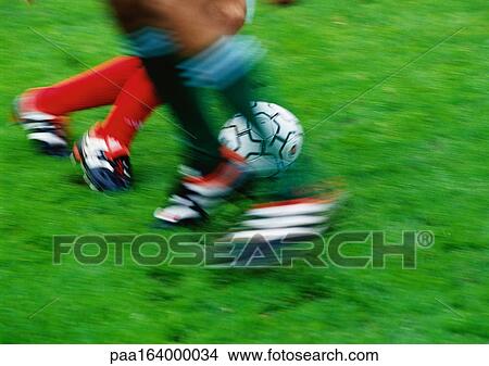 Two soccer players running for ball, low section, blurred. View Large Photo Image Picture - Two soccer players running for ball, low section, blurred.. Fotosearch