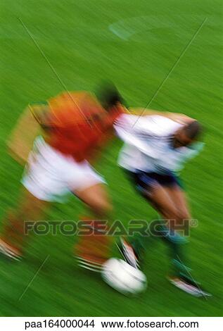 Picture - Two soccer players running with ball, blurred.. Fotosearch