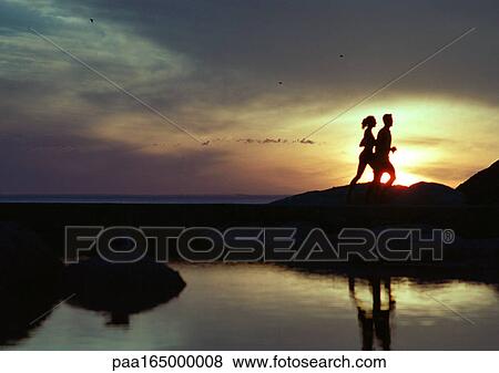 Couple running near water at sunset, silhouette View Large Photo Image Stock Photo - Couple running near water at sunset, silhouette. Fotosearch