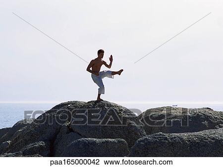 Man doing tai chi on a rock near the sea. View Large Photo Image Stock Image - Man doing tai chi on a rock near the sea.. Fotosearch
