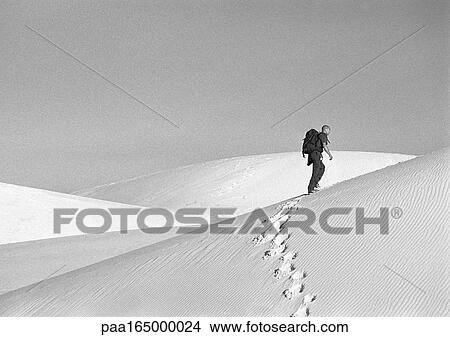 Man hiking across dune, side view, b&w. View Large Photo Image Picture - Man hiking across dune, side view, b&w.. Fotosearch