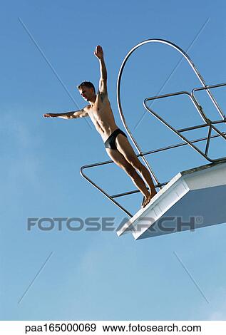 Man standing on diving board, low angle view. View Large Photo Image Stock Photo - Man standing on diving board, low angle view.. Fotosearch