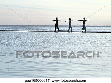 Three people exercising by the sea. View Large Photo Image Stock Photo - Three people exercising by the sea.. Fotosearch