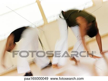 Stock Photo - Two men performing capoeira, blurred. Fotosearch
