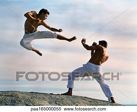 Two men practicing martial arts, one in mid-air. View Large Photo Image Stock Photography - Two men practicing martial arts, one in mid-air.. Fotosearch