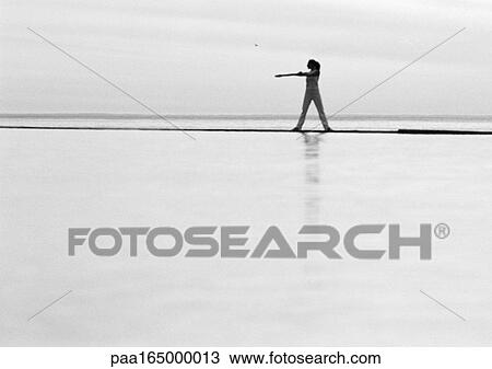 Stock Image - Woman exercising by the sea, b&w.. Fotosearch