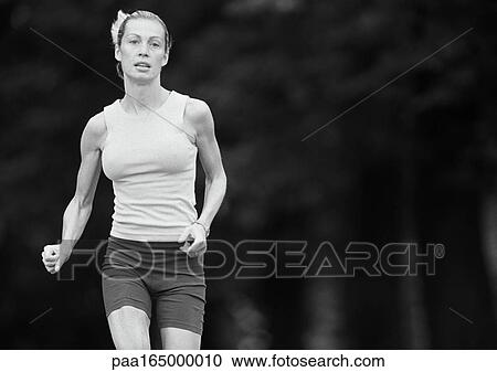 Stock Image - Woman in sports clothes running, three quarter length, b&w. Fotosearch