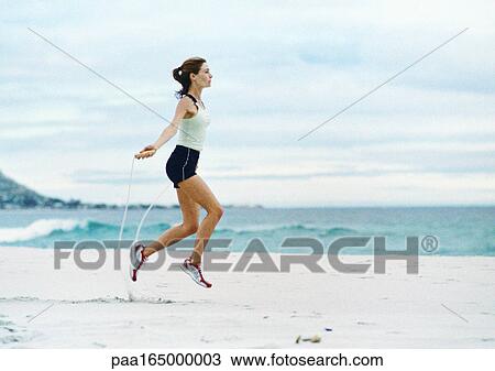 Woman jumping rope on beach, side view. View Large Photo Image Stock Image - Woman jumping rope on beach, side view.. Fotosearch