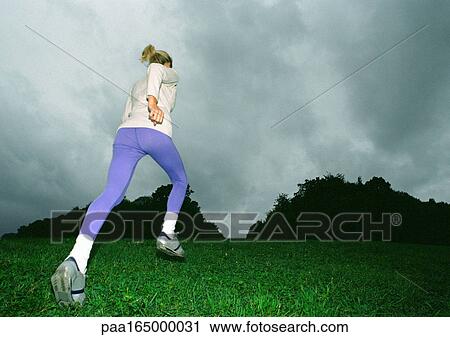 Woman running on grass, rear view, full length, low angle view, silhouette of trees in background View Large Photo Image Stock Image - Woman running on grass, rear view, full length, low angle view, silhouette of trees in background. Fotosearch