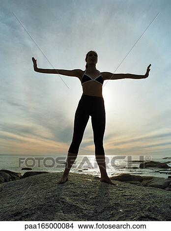 Woman standing on beach, arms extended out, silhouette. View Large Photo Image Picture - Woman standing on beach, arms extended out, silhouette.. Fotosearch